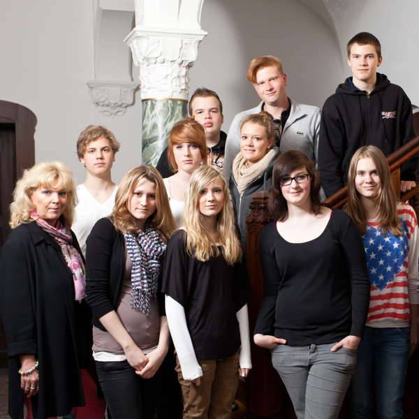 Eine Gruppe von Schülern im Holztreppenhaus der Privatschule Bonn. Privatschule ist ein Konzept, das Früchte trägt.